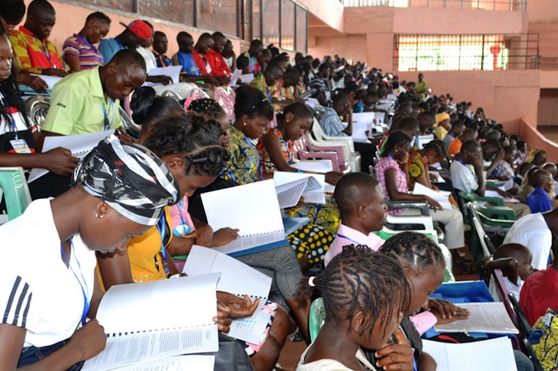 Large group of youth studying material together.