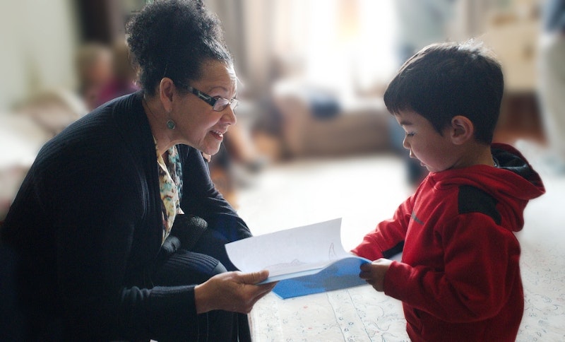 young boy shows his drawing to a teacher